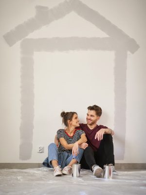 Vertical image of caucasian couple resting after wall painting of the new house